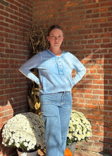 Load image into Gallery viewer, Person lying on a brick floor with pumpkins and flowers