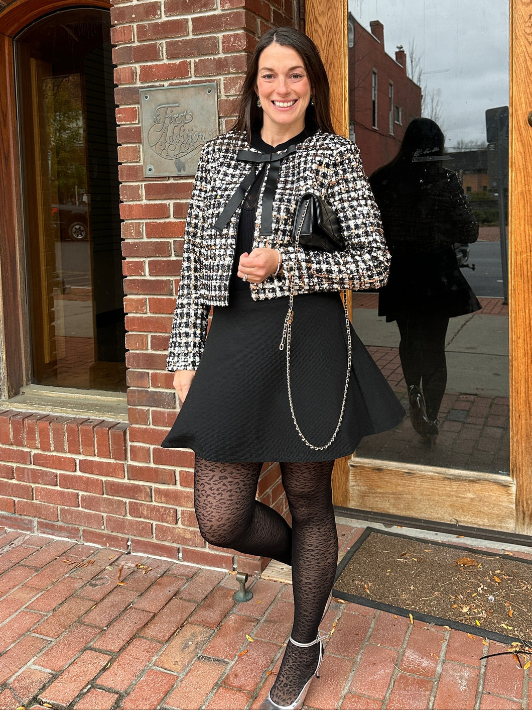Person standing in front of a brick building with wooden doors.