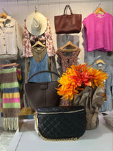 Load image into Gallery viewer, Display of clothing and bags with a black quilted handbag in the foreground.

